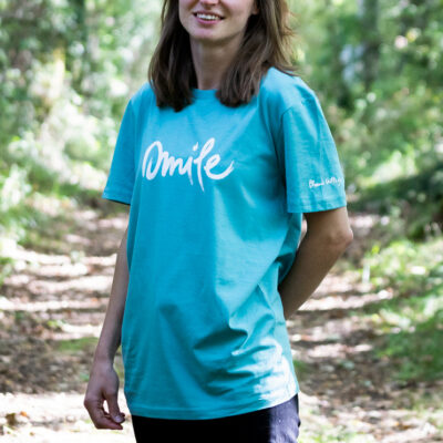 Person wearing Plum Village T‑shirt ‘Smile’ in a peaceful garden setting