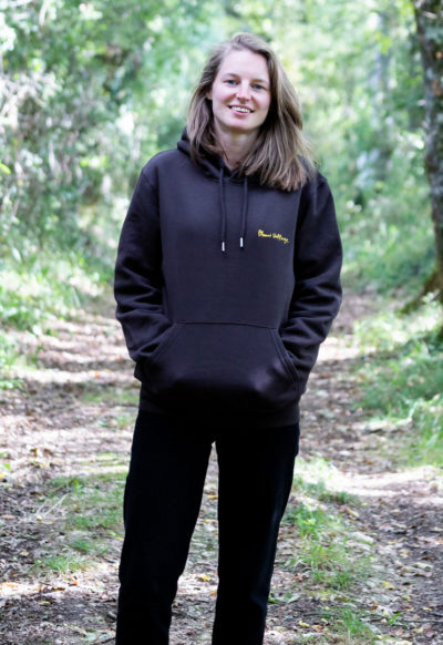 Person wearing a Plum Village Hoodie in a forest, highlighting 100% organic cotton - Wake Up