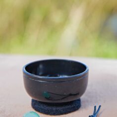 Mini bell for desk meditation with healing stones — small Japanese mindfulness bell being invited to sound