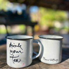 A Plum Village Enamel Mug, featuring Thich Nhat Hanh’s calligraphy, sits on a rustic table