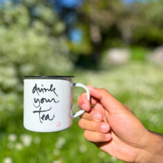 A white Plum Village Enamel Mug, featuring Thich Nhat Hanh’s calligraphy