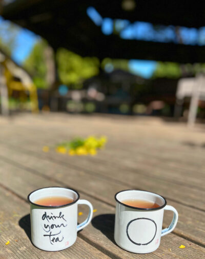 The Plum Village Enamel Mug, adorned with Thich Nhat Hanh’s “Drink your tea” calligraphy and the Enso Circle