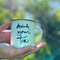 The Plum Village Enamel Mug, with Thich Nhat Hanh’s “Drink your tea” calligraphy, glows in soft light