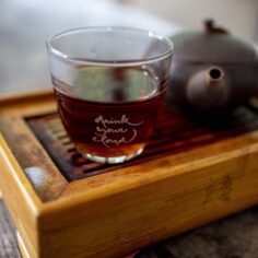 Close-up of the Plum Village Tea Glass, showcasing its crystal clarity and engraved quote, with a warm cup of tea inside