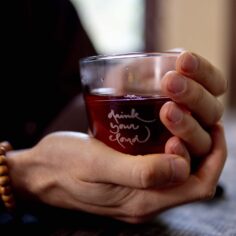 Close-up of the Plum Village Tea Glass, showcasing its crystal clarity and engraved quote, with a warm cup of tea inside