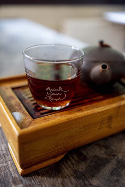 Close-up of the Plum Village Tea Glass, showcasing its crystal clarity and engraved quote, with a warm cup of tea inside