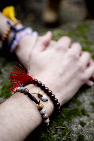 Plum Village wrist mala collection featuring different materials: light wood, jasper, lapis lazuli, and rose quartz, displayed on a natural surface