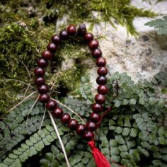 Dark wood wrist mala close-up, showcasing 27 smooth wooden beads and a sleek adjustable string for a comfortable fit