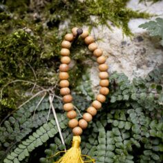 Light wood wrist mala close-up, showcasing 27 smooth wooden beads and a sleek adjustable string for a comfortable fit