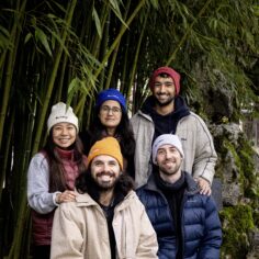 Model wearing the Plum Village organic cotton beanie in a forest setting