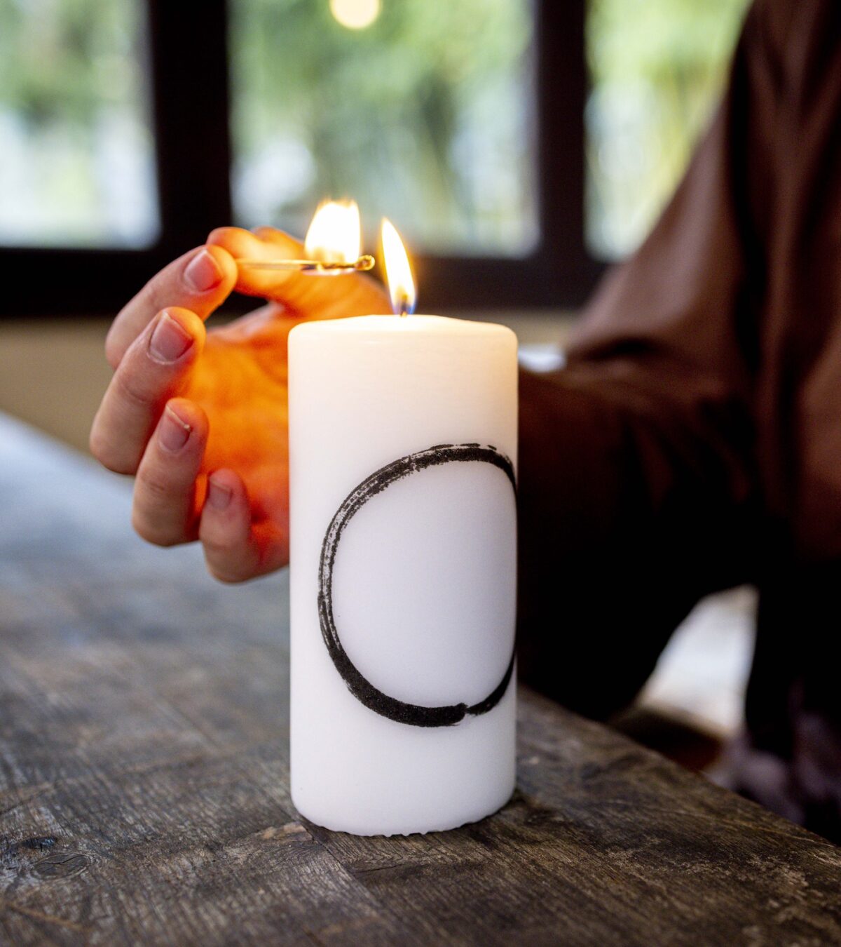 The Plum Village Mindfulness Candle featuring Thich Nhat Hanh’s Zen Circle Calligraphy, glowing softly in a minimalist space