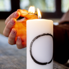 The Plum Village Mindfulness Candle featuring Thich Nhat Hanh’s Zen Circle Calligraphy, glowing softly in a minimalist space