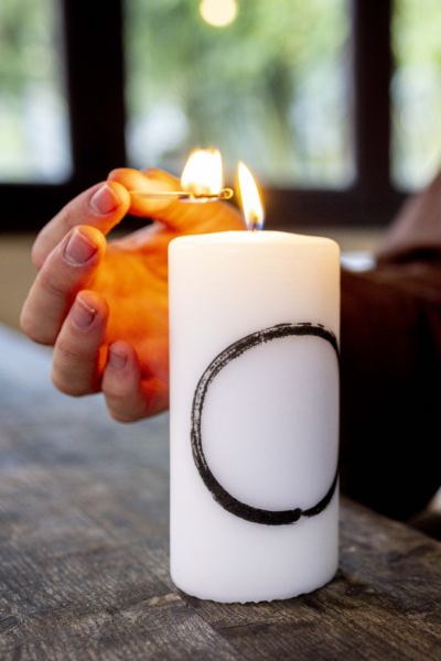 The Plum Village Mindfulness Candle featuring Thich Nhat Hanh’s Zen Circle Calligraphy, glowing softly in a minimalist space